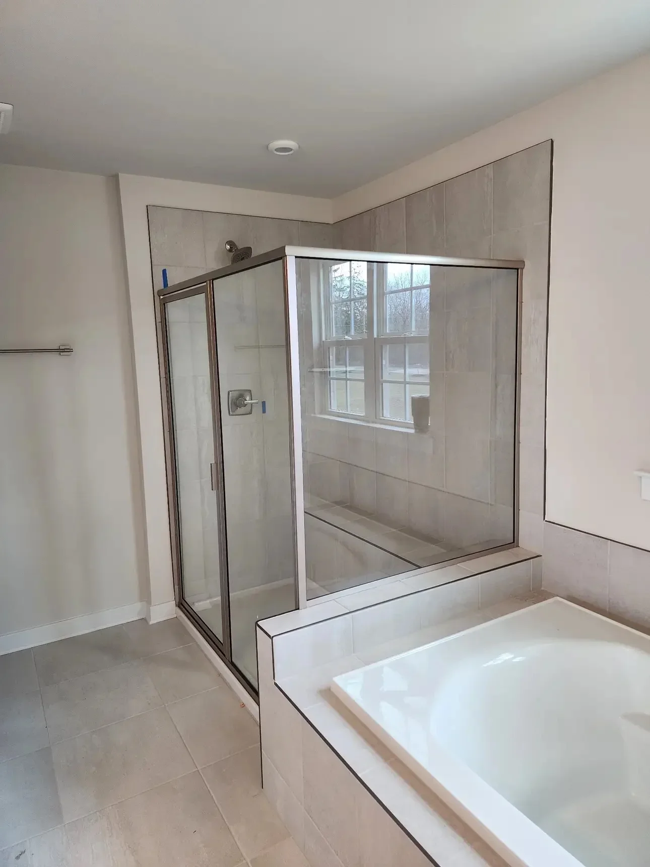 Frameless glass shower enclosure with brushed nickel hardware and white subway tile surround